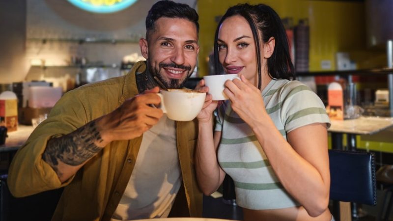 heterosexual-couple-looking-at-camera-drinking-cof-2023-11-27-05-36-32-utc-min